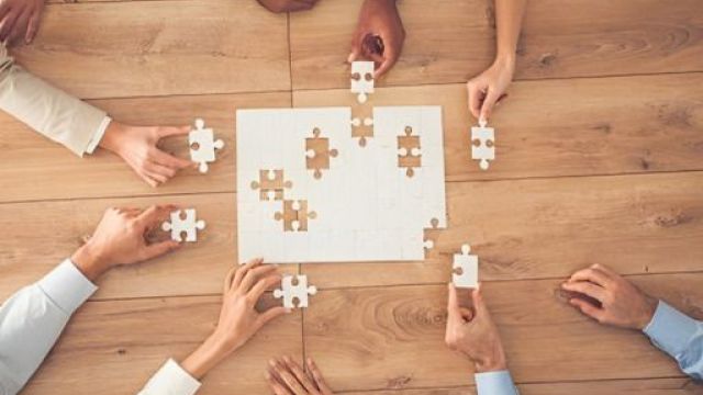 Mani di varie persone che fanno un puzzle