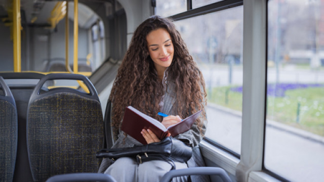 Ragazza seduta all'interno di un bus con un libro tra le mani
