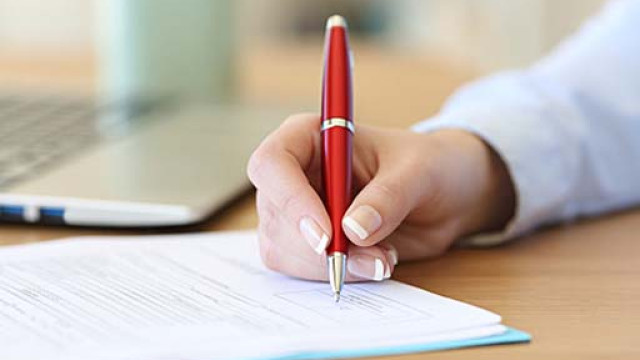 inquadratura di una mano con la penna che firma dei documenti