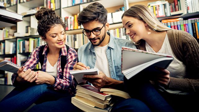 Tre studenti seduti all'interno di una biblioteca