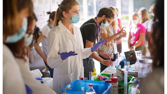 Notte ricercatori settembre 2021 Una ricercatrice in camice bianco mostra un esperimento al pubblico in occasione della Notte dei ricercatori