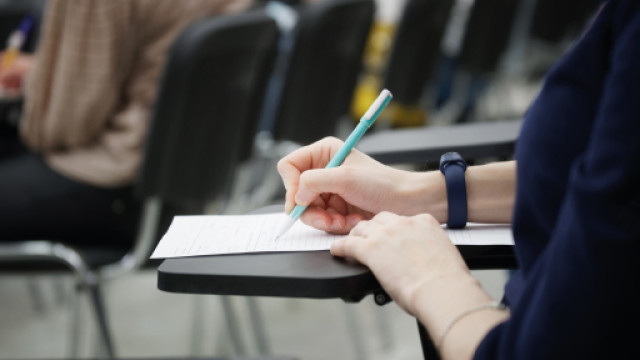Mano femminile che scrive su un foglio Mano femminile che scrive su un foglio