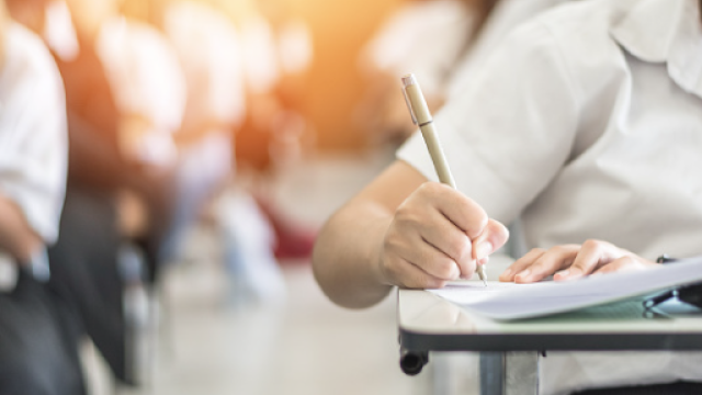 mano di una persona che scrive, seduta ad un banco