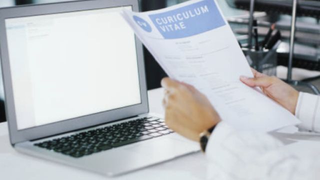 immagine con una persona che legge un cv davanti a pc