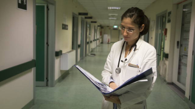 dottoressa con camice e stetoscopio, legge una cartella