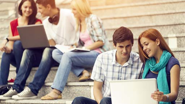 Studenti seduti sulle scale che guardano il computer 
