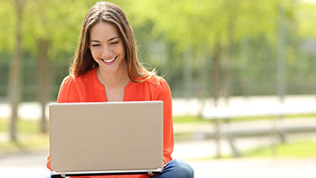 Ragazza all'aperto che consulta il proprio laptop