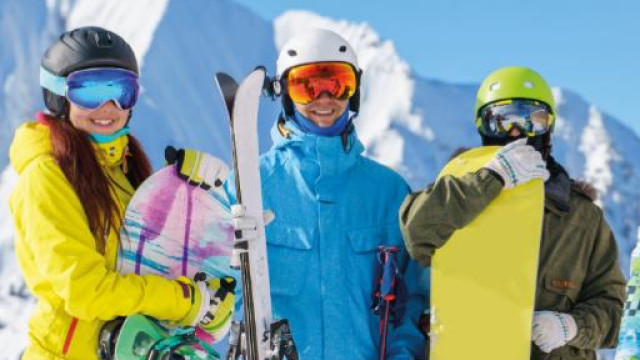 Fotografia di tre persone giovani vestite da neve con snowbord e sci, sullo sfondo montagne innevate