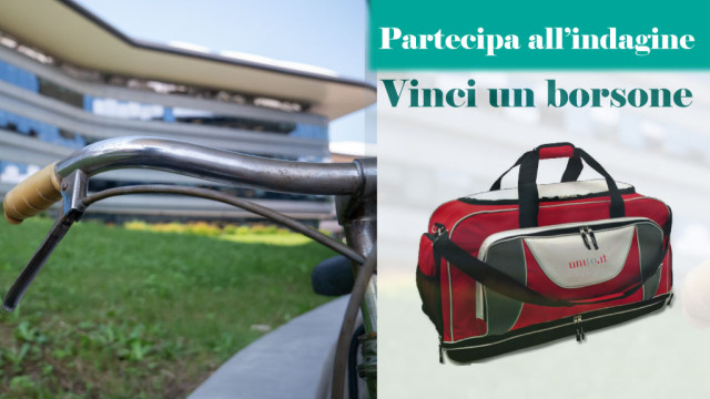 Il manubrio di una bici, sullo sfondo il CLE, e a lato uno dei borsoni in palio