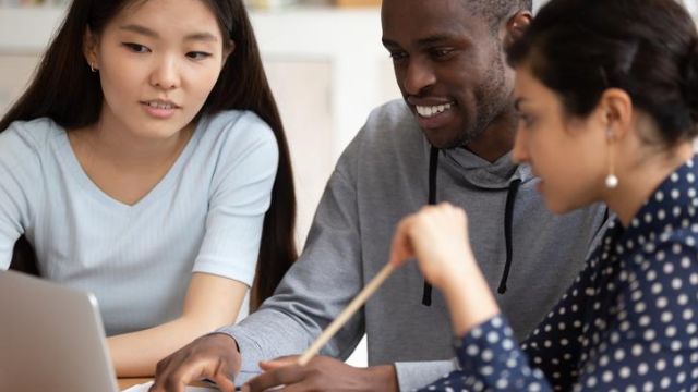 Studenti di varie nazionalità che guardano insieme un computer Studenti di varie nazionalità che guardano insieme un computer