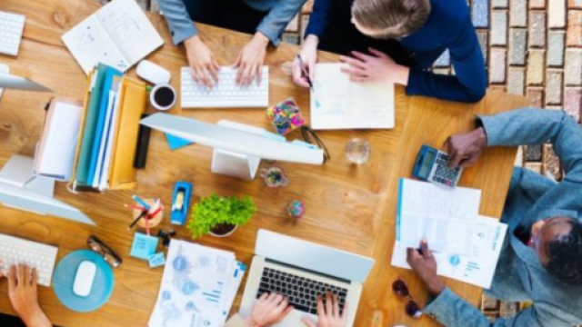 Immagine decorativa. Persone sedute attorno ad un tavolo di lavoro con pc, penne e quaderni