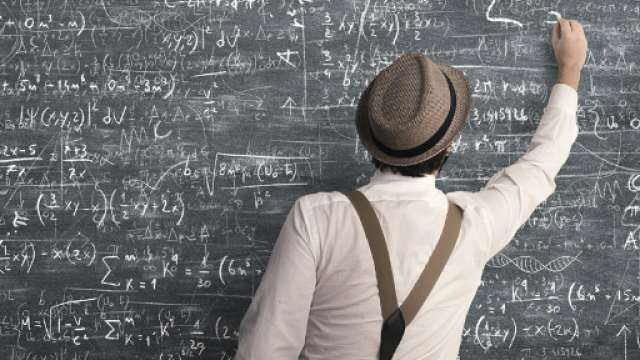 Di spalle un uomo scrive alla lavagna 