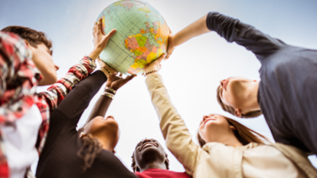 Studentesse e studenti si allungano insieme verso un mappamondo