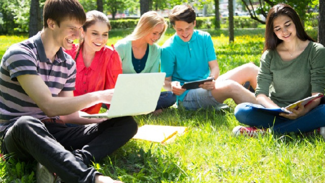 studenti con pc portatile, seduti su un prato
