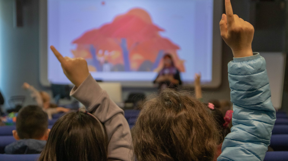 bambine che alzano la mano in aula con docente