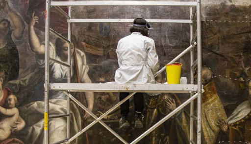 restauratrice su impalcatura di fronte a un dipinto