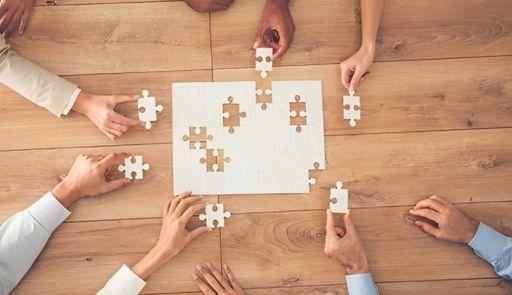 Mani di varie persone che fanno un puzzle