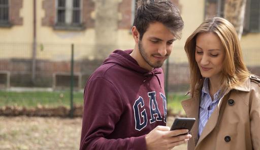 Un ragazzo e una ragazza in un parco guardano il cellulare