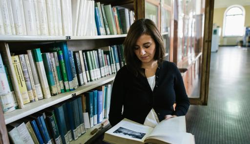 Dottorando che legge in biblioteca