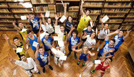 Studenti sportivi che lanciano dei fogli in alto in una biblioteca