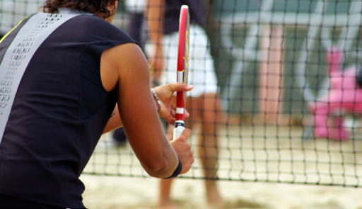 Atleta di spalle con racchetta in mano sul campo di beach tennis