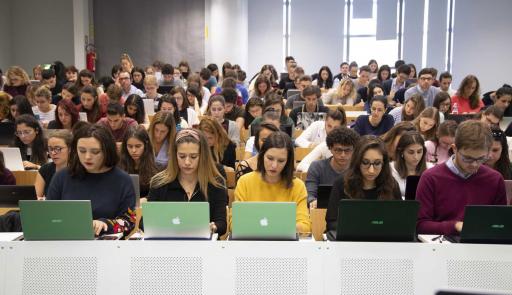 Aula piena di studenti con laptop aperti sui banchi