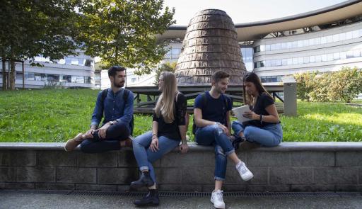 Studenti e studentesse seduti su di un muretto intenti a chiaccherare