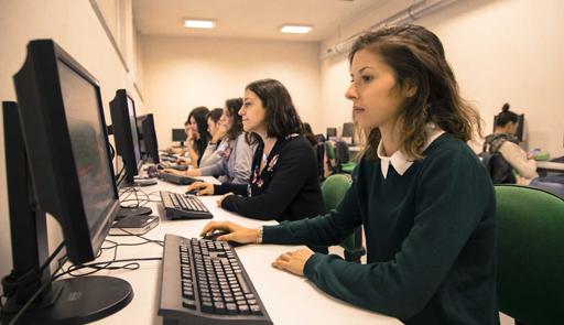 Studentesse sedute in fila che studiano al computer