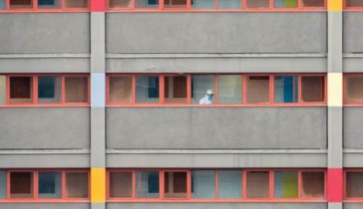 Visuale di un condominio dall'esterno con una persona in tuta anticontagio su di un balcone