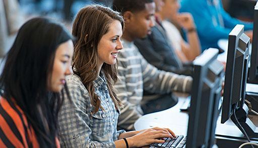 Studentesse e studenti, seduti in fila una accanto all'altra, che lavorano al computer