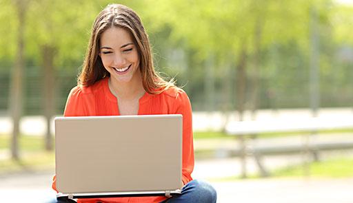 Ragazza all'aperto che consulta il proprio laptop