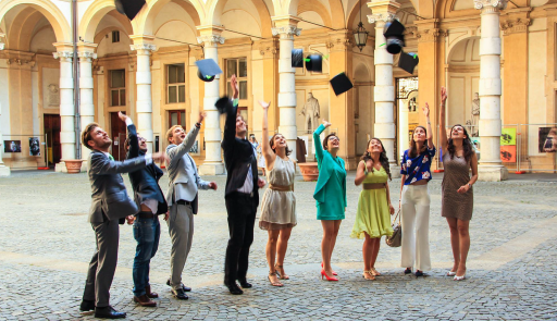 Studenti e studentesse nel cortile del Rettorato che festeggiano il conseguimento del titolo lanciando nell'aria i loro cappelli di laurea