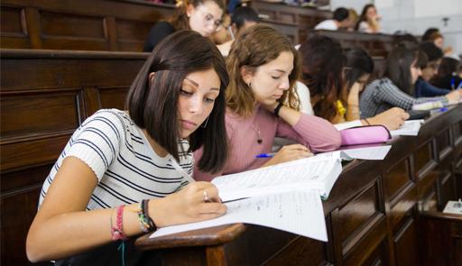 Studentesse sedute in aula di lezione, con una studentessa in primo piano che prende appunti