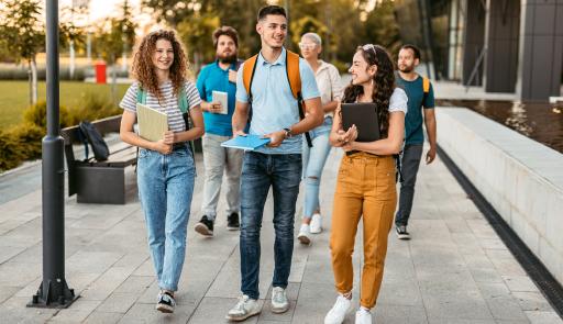 Studenti sorridenti che camminano con libri in mano e zaini sulle spalle