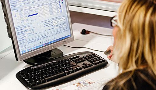 Una donna seduta a una scrivania con di fronte il monitor di un pc