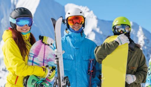 Tre giovani sciatori vestiti da neve e con sci e snowboard