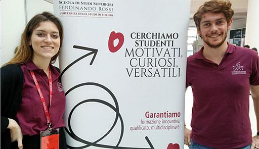 Un ragazzo e una ragazza sorridono di fianco al totem della Scuola Ferdinando rossi
