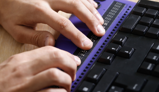 Immagine che illustra due mani che usano una tastiera di un pc che ha incorporata una base con i tasti braille