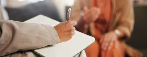 Mano in primo piano che scrive su di un foglio bianco