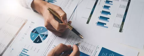 Due persone scorrono dei fogli con dei grafici