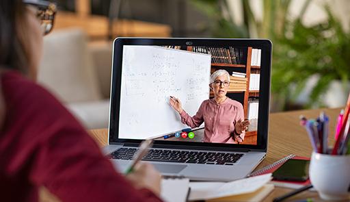 iStock / Getty Images Plus / Ridofranz Studentessa al computer e sul display la docente che tiene una lezione online