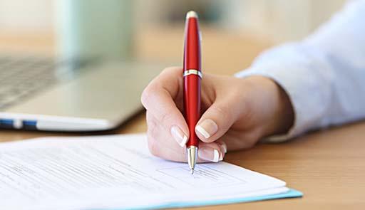 inquadratura di una mano con la penna che firma dei documenti