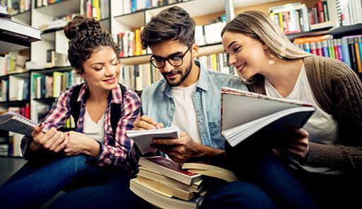 Tre studenti seduti all'interno di una biblioteca
