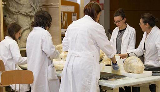 Prima edizione - 14 febbraio 2020 Ricercatrici con il camice lavorano con degli oggetti disposti sopra un tavolo