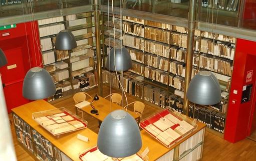 interno dell'Archivio storico, scaffali colmi di libri antichi e bacheche che espongono i materiali più delicati