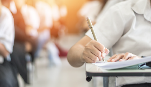 mano di una persona che scrive, seduta ad un banco