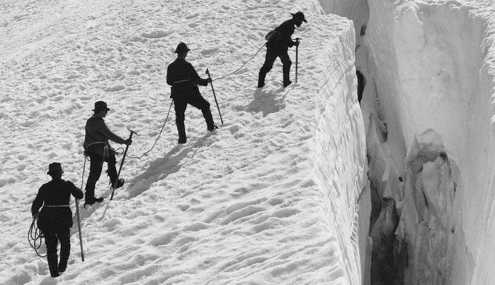 Foto in bianco e nero di 4 alpini a bordo di un crepaccio