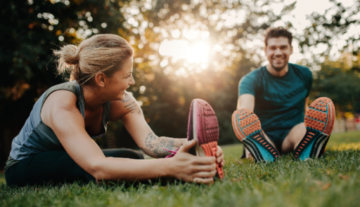 Torino OnMove – Il progetto che porta i professionisti del #CUSTorino nei parchi torinesi foto di due sportivi, un ragazzo e una ragazza che fanno stretching su un prato