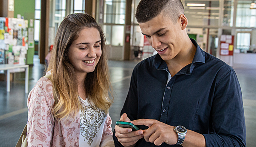 Due giovani studenti consultano lo smartphone