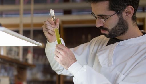 ricercatore all'interno di un laboratorio chimico, ha in mano una provetta con del liquido
